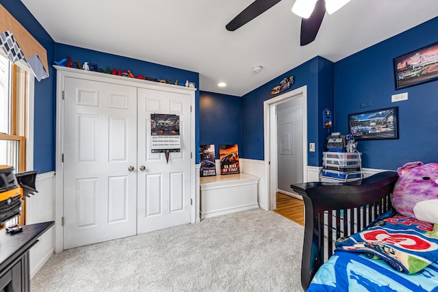 bedroom with carpet, a closet, ceiling fan, and wainscoting