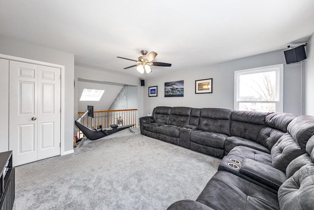 carpeted living room with ceiling fan and a skylight