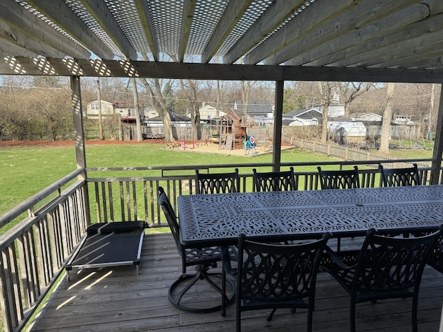 wooden terrace featuring fence, outdoor dining area, a yard, and a playground