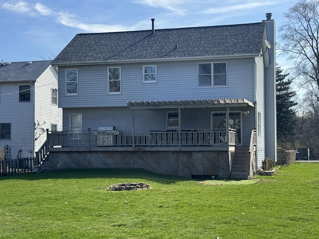 rear view of house with a fire pit, a chimney, a deck, and a lawn
