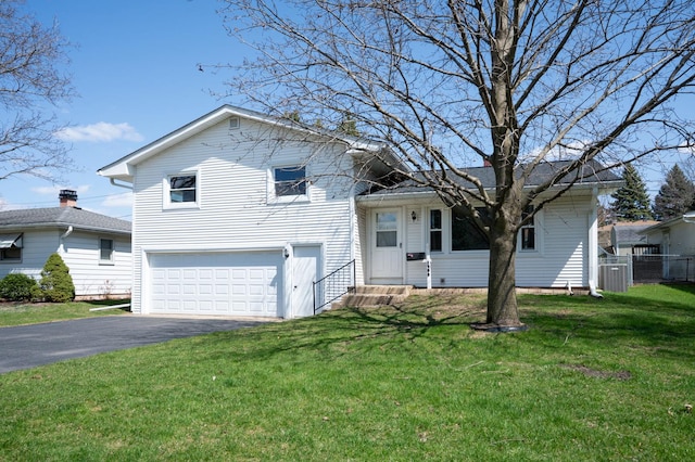 tri-level home featuring fence, a front lawn, entry steps, an attached garage, and driveway