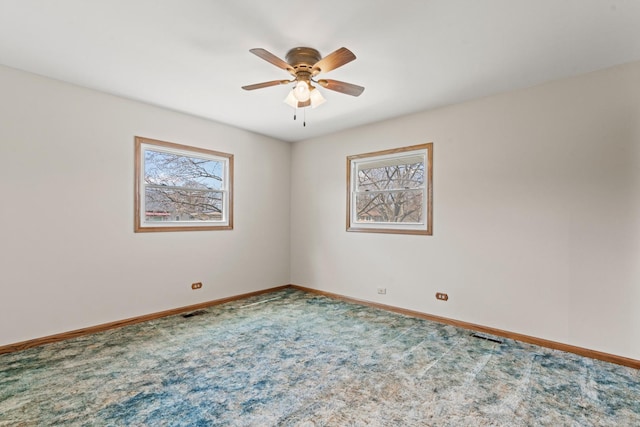 carpeted empty room with a ceiling fan and baseboards