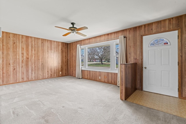 entryway with ceiling fan, wood walls, and light carpet