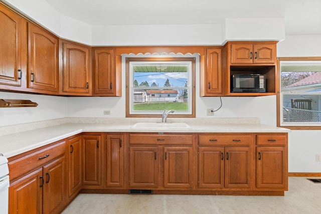 kitchen featuring brown cabinets, light countertops, visible vents, a sink, and black microwave