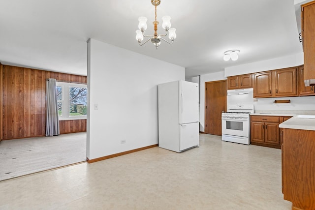 kitchen featuring brown cabinets, a chandelier, white appliances, light countertops, and range hood