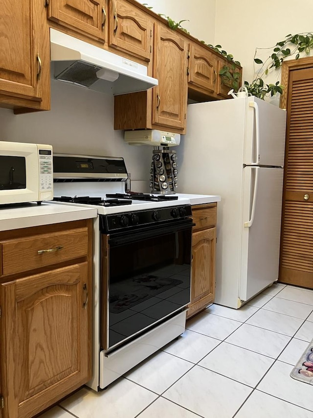 kitchen featuring under cabinet range hood, white appliances, light countertops, and brown cabinets