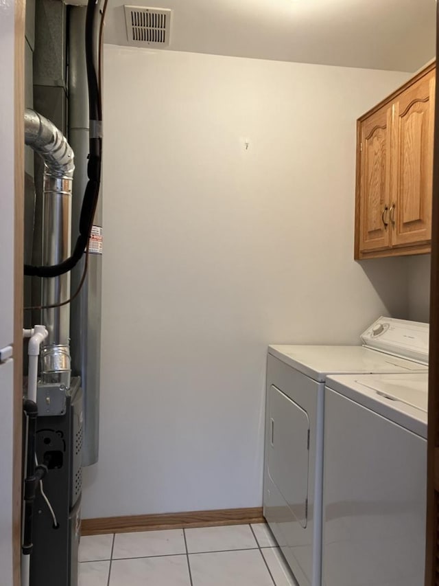 laundry room featuring baseboards, light tile patterned floors, visible vents, washer and clothes dryer, and cabinet space