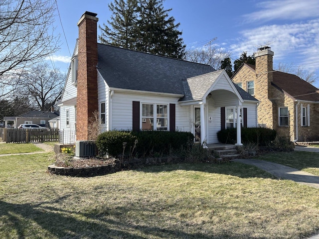 view of front of home featuring cooling unit, a chimney, a front yard, and fence