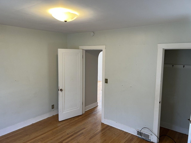 unfurnished bedroom featuring a closet, visible vents, baseboards, and wood finished floors