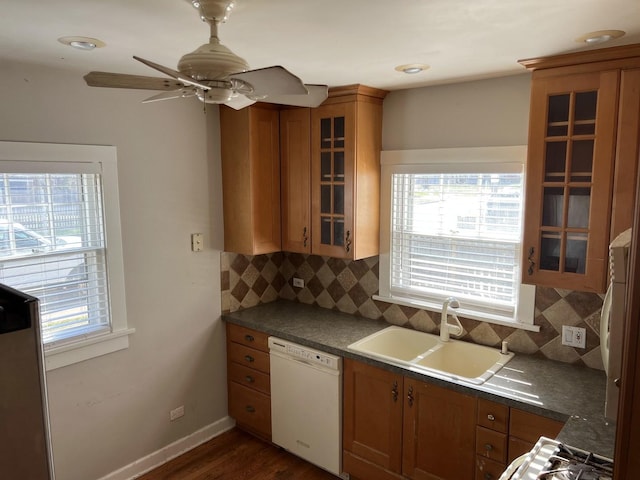 kitchen with white dishwasher, brown cabinets, a sink, and backsplash