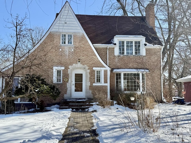 tudor home with brick siding and a chimney