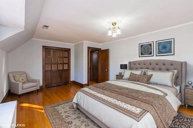 bedroom with baseboards, an inviting chandelier, ornamental molding, and wood finished floors