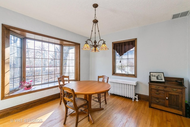 dining area with light wood-style flooring, visible vents, baseboards, and radiator