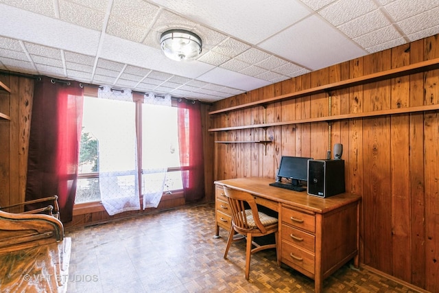 office space featuring wood walls and a paneled ceiling