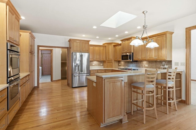 10440 Deer Chase Ave, Orland Park, IL 60467 - kitchen featuring a skylight, light wood-style floors, a peninsula, and stainless steel appliances