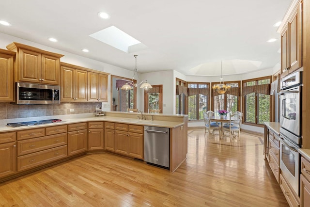 10440 Deer Chase Ave, Orland Park, IL 60467 - kitchen featuring a peninsula, a skylight, appliances with stainless steel finishes, a sink, and a notable chandelier