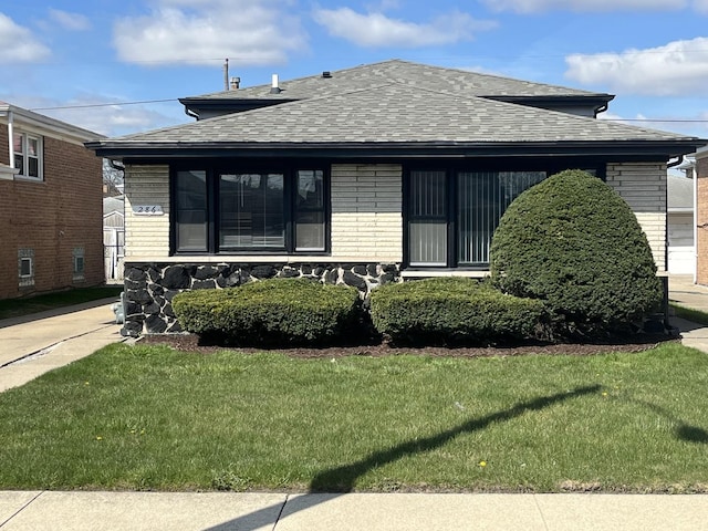 bungalow-style house featuring brick siding, a shingled roof, and a front yard