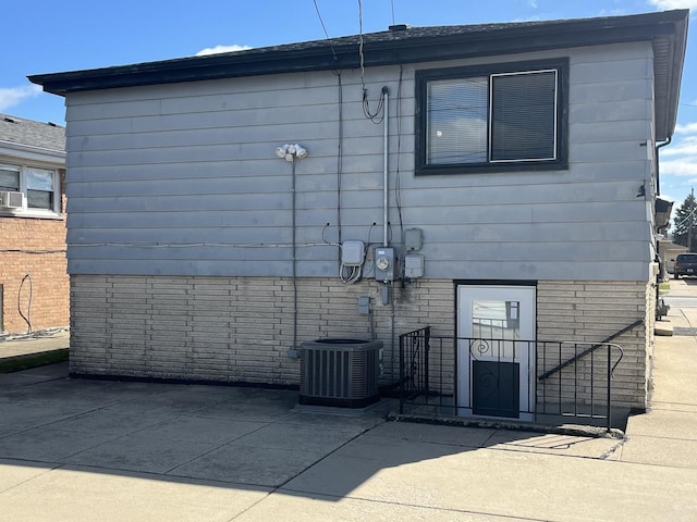 back of house with brick siding, central AC, and a patio area