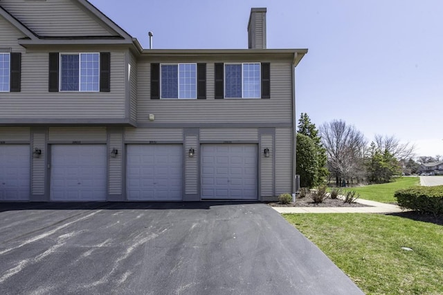 view of home's exterior with an attached garage, a chimney, and a lawn
