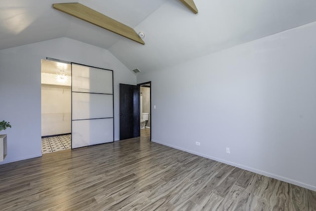interior space featuring wood finished floors, visible vents, baseboards, and vaulted ceiling