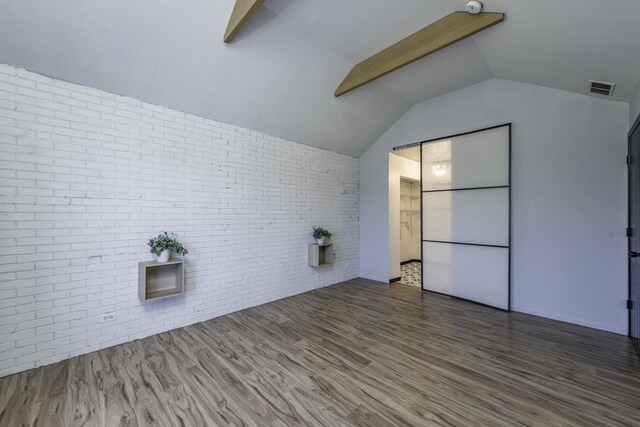 bonus room featuring brick wall, wood finished floors, vaulted ceiling, and visible vents