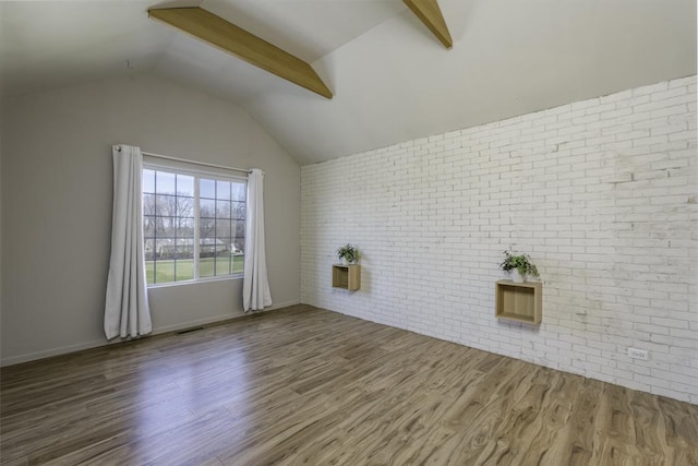 spare room featuring visible vents, brick wall, wood finished floors, and vaulted ceiling
