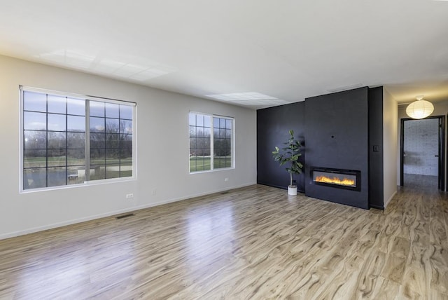 unfurnished living room featuring baseboards, wood finished floors, a fireplace, and visible vents