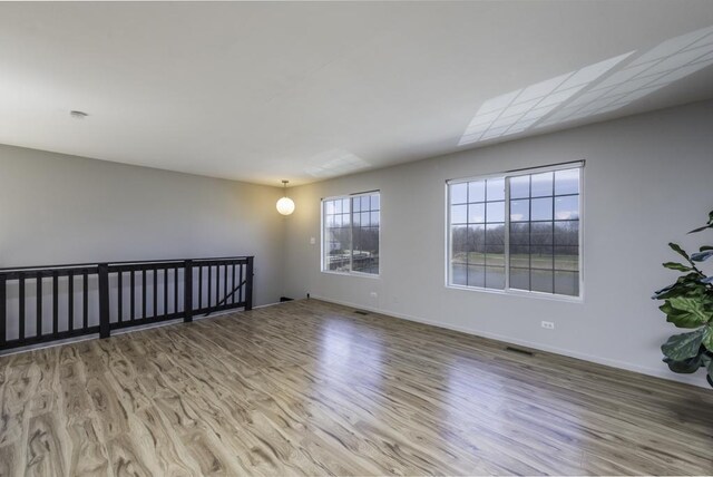 unfurnished room featuring visible vents, baseboards, and wood finished floors