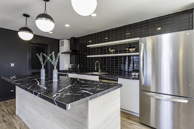 kitchen featuring modern cabinets, wall chimney range hood, open shelves, appliances with stainless steel finishes, and a sink