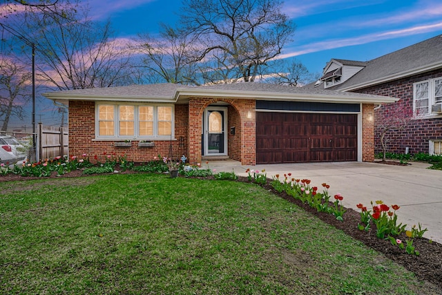 view of front facade with a front lawn, concrete driveway, fence, brick siding, and an attached garage