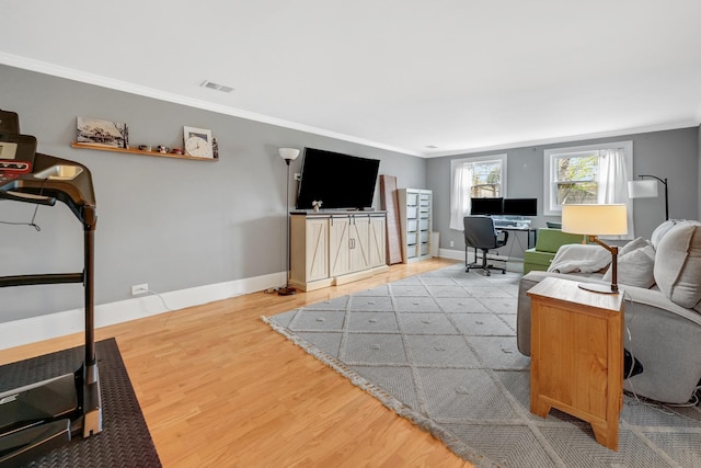 living room with light wood-type flooring, visible vents, crown molding, and baseboards