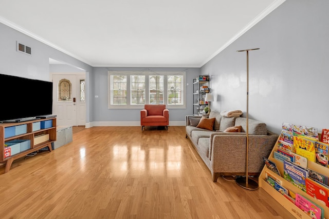 living area with light wood finished floors, visible vents, crown molding, and baseboards