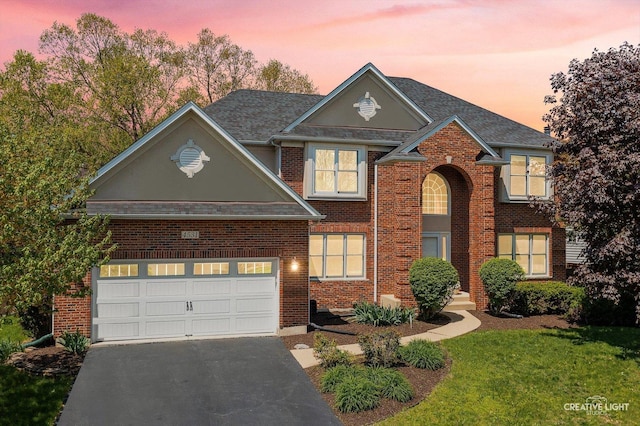 traditional home featuring driveway, brick siding, a lawn, and a shingled roof