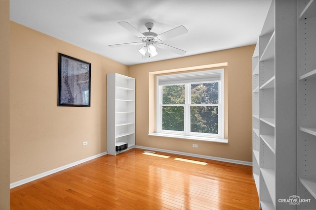 spare room with light wood-type flooring, baseboards, and a ceiling fan