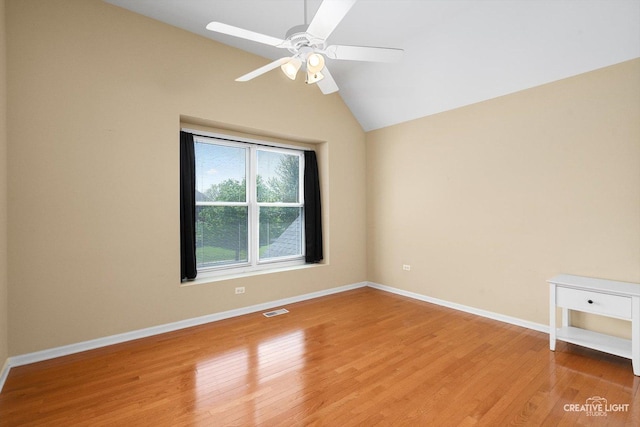 spare room featuring light wood-style floors, ceiling fan, vaulted ceiling, and baseboards