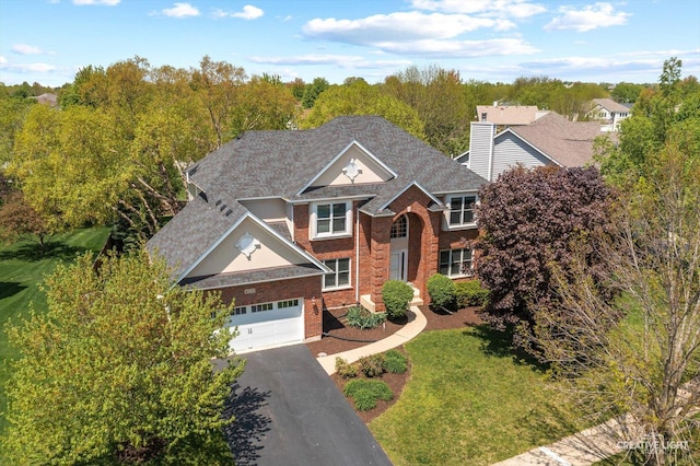 traditional-style house with brick siding, driveway, a front lawn, roof with shingles, and an attached garage