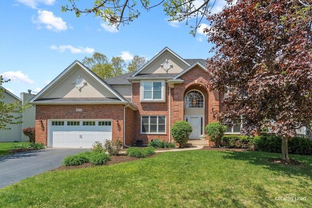 traditional-style home featuring asphalt driveway, brick siding, a front yard, and an attached garage