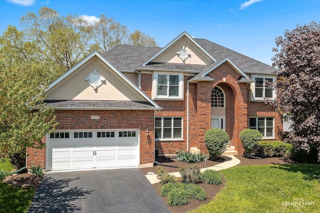 traditional home with driveway, brick siding, a front lawn, and a shingled roof
