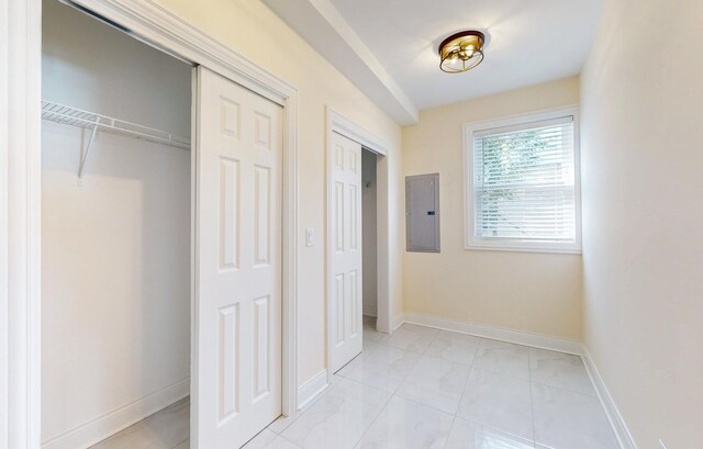 unfurnished bedroom with electric panel, baseboards, marble finish floor, and multiple closets