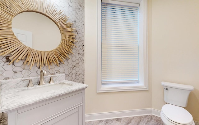 bathroom featuring toilet, vanity, baseboards, and decorative backsplash
