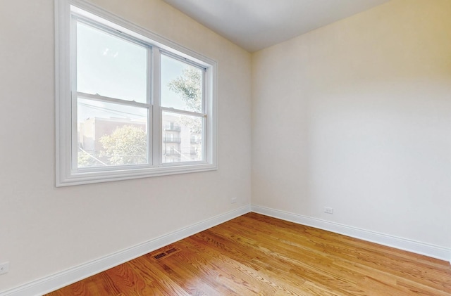 empty room with light wood-style flooring, baseboards, and visible vents