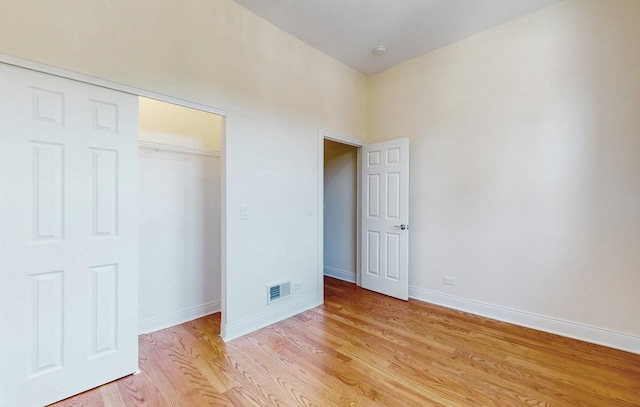 unfurnished bedroom with light wood-style flooring, a closet, baseboards, and visible vents