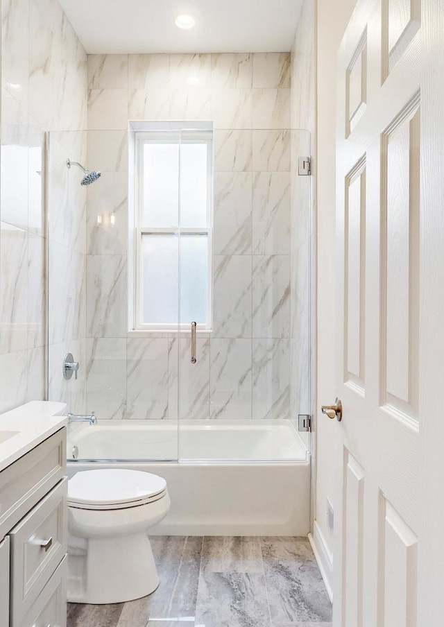 full bath with toilet, vanity, combined bath / shower with glass door, and plenty of natural light