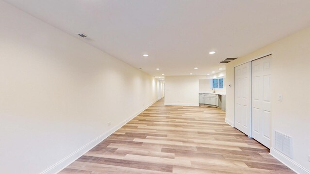 hallway with light wood-style flooring, baseboards, visible vents, and recessed lighting
