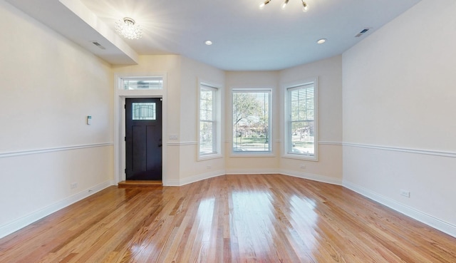 entryway featuring visible vents, baseboards, light wood-type flooring, and a notable chandelier