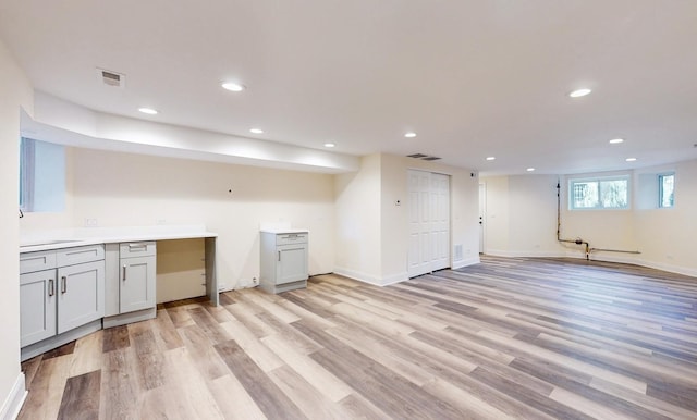 basement featuring light wood-type flooring, baseboards, visible vents, and recessed lighting