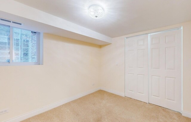 below grade area with light carpet, baseboards, and visible vents