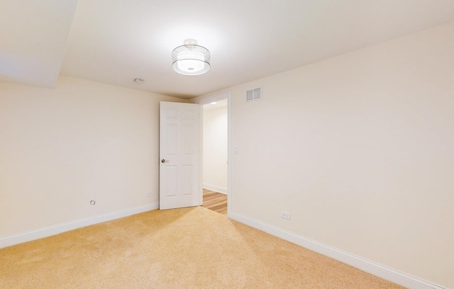 empty room featuring light colored carpet, baseboards, and visible vents