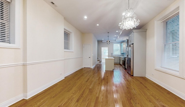 interior space with light wood-type flooring, baseboards, a chandelier, recessed lighting, and visible vents