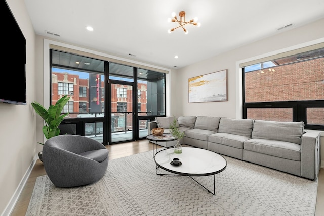 living area featuring wood finished floors, baseboards, visible vents, and a notable chandelier